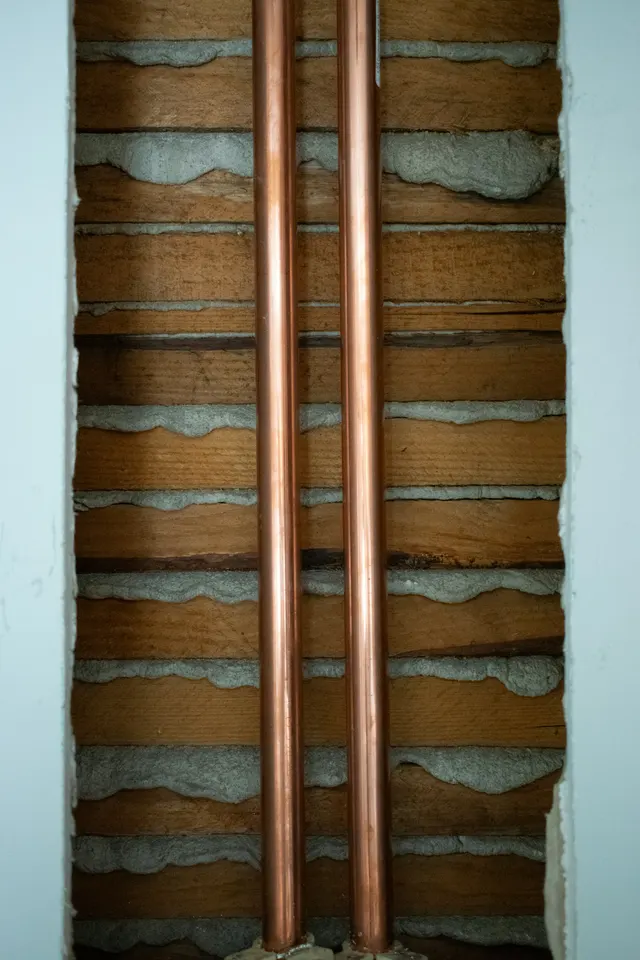 Copper pipes visible through an opened interior wall